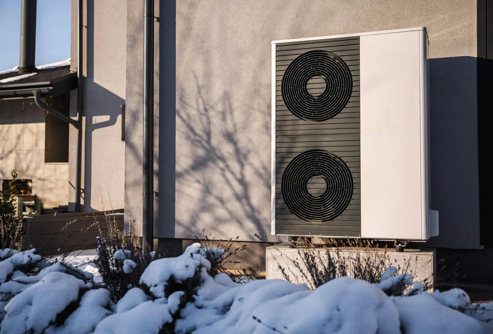 Pompe à chaleur aérothermique installée devant une maison en hiver